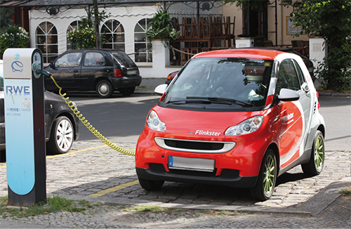 Rotes Elektroauto parkt an einer Ladestation auf der Straße.