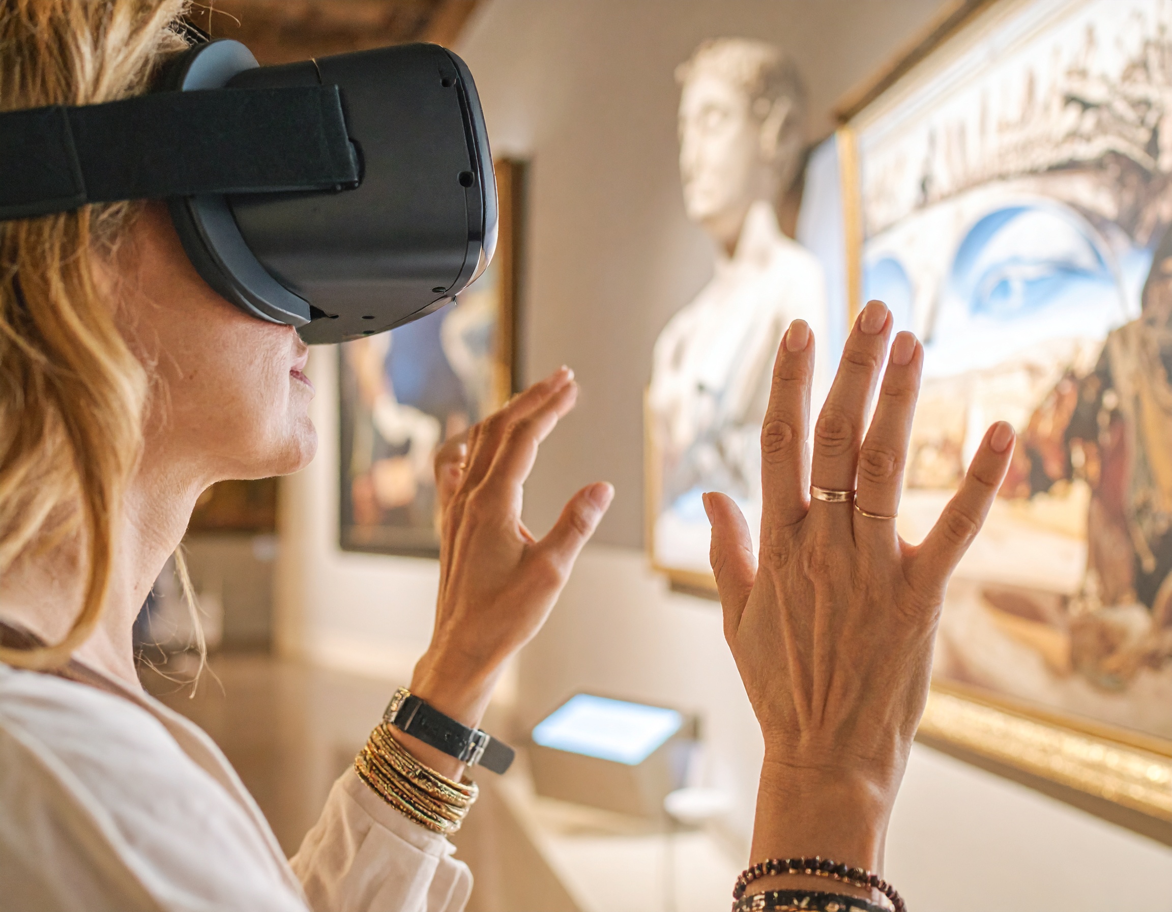 Frau mit VR-Brille im Kunstmuseum, interagiert mit digitalen Kunstwerken.