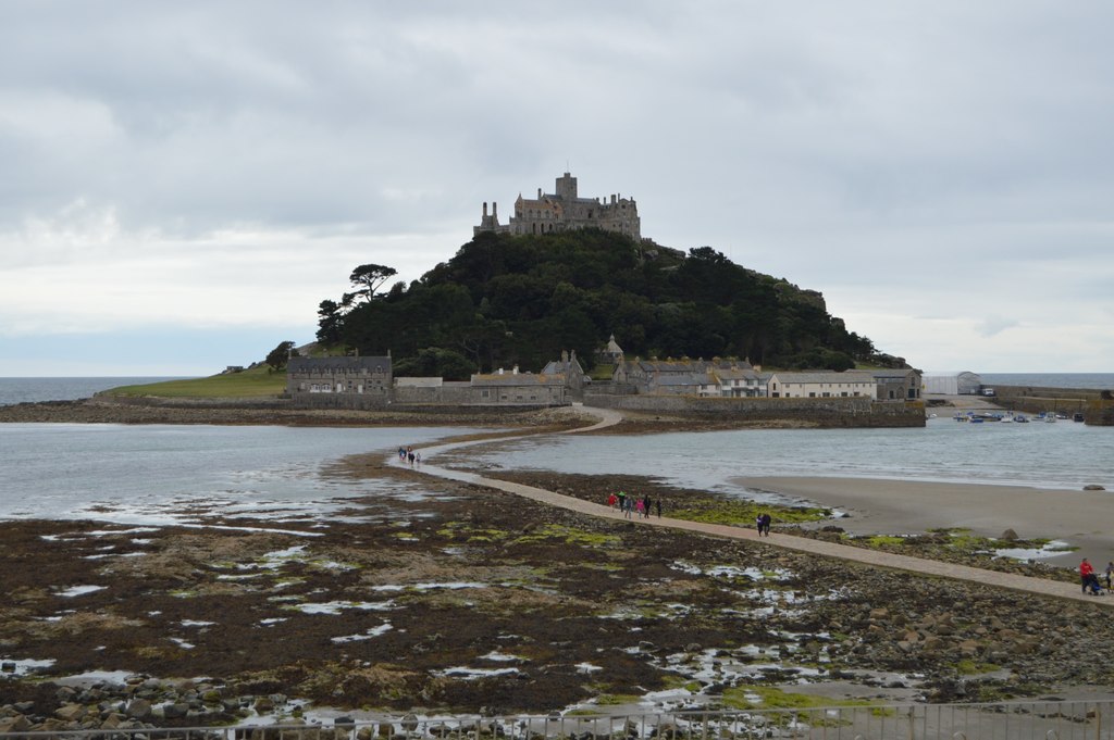 Eine Insel mit einem Schloss, umgeben von Wasser und Land, mit einigen Menschen auf einem Weg.