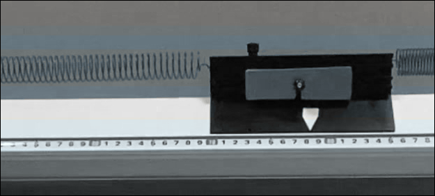Mechanisches Messgerät mit Feder und verschiebbarem Gewicht.