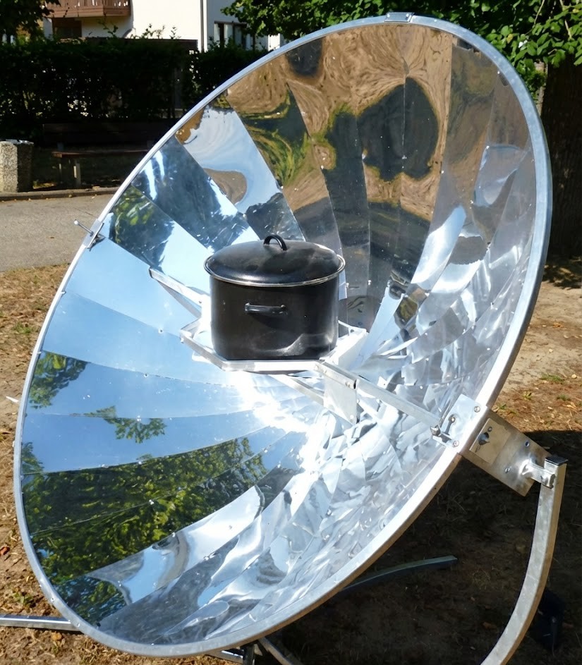 Parabolischer Solarkocher mit reflektierender Schüssel und schwarzem Kochtopf im Freien
