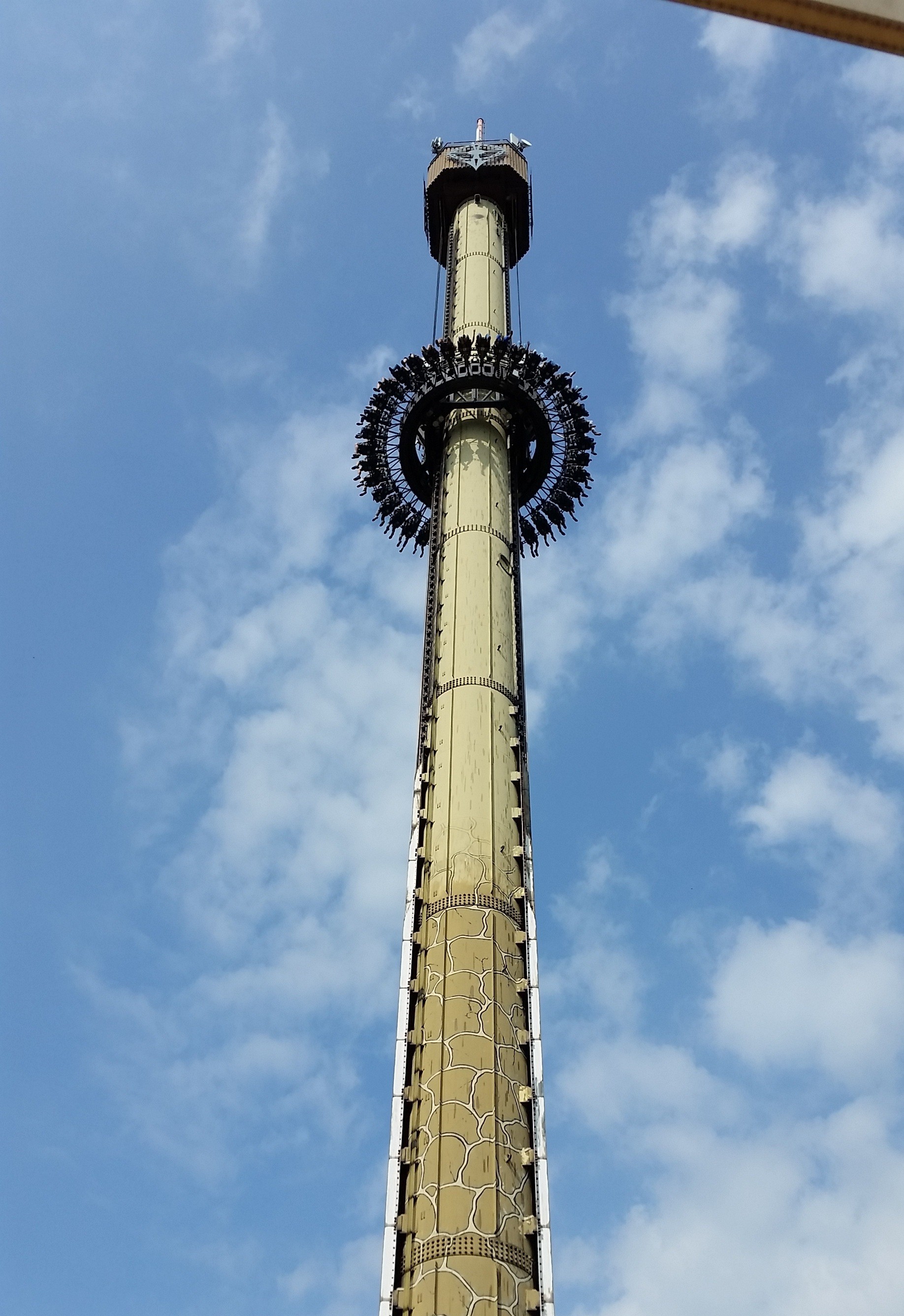 Hoher Fallturm mit rundem Sitzring vor blauem Himmel