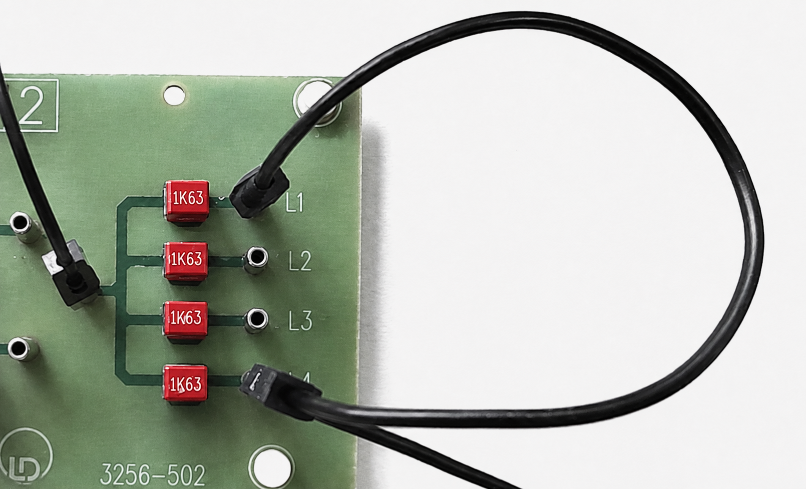 Elektronische Platine mit angeschlossenen Kabeln und roten Bauteilen.