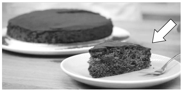 Ein Stück Schokoladenkuchen auf einem Teller mit Gabel, im Hintergrund ein ganzer Kuchen.