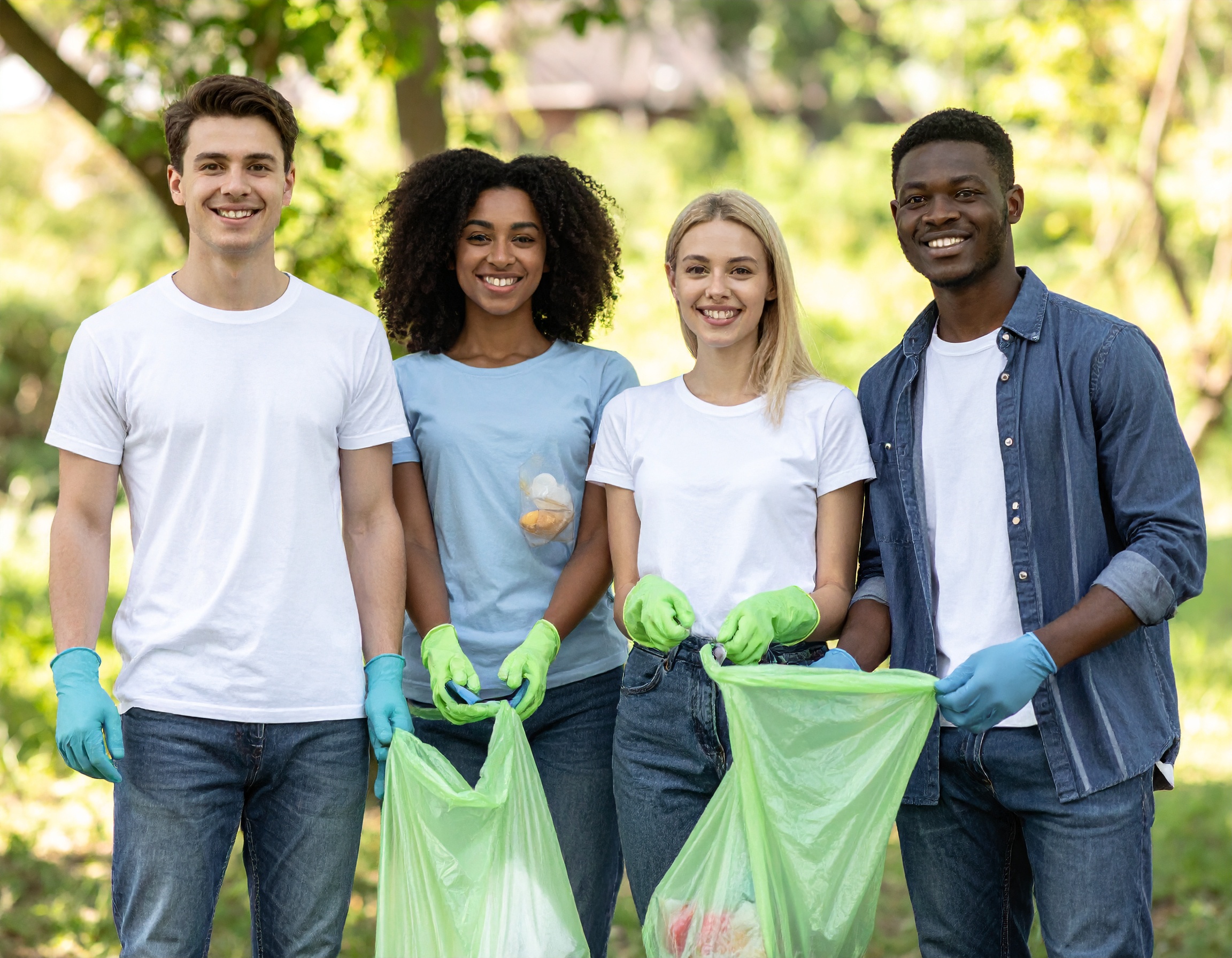 Gruppe junger Menschen mit Handschuhen hält Müllsäcke in einem Park.