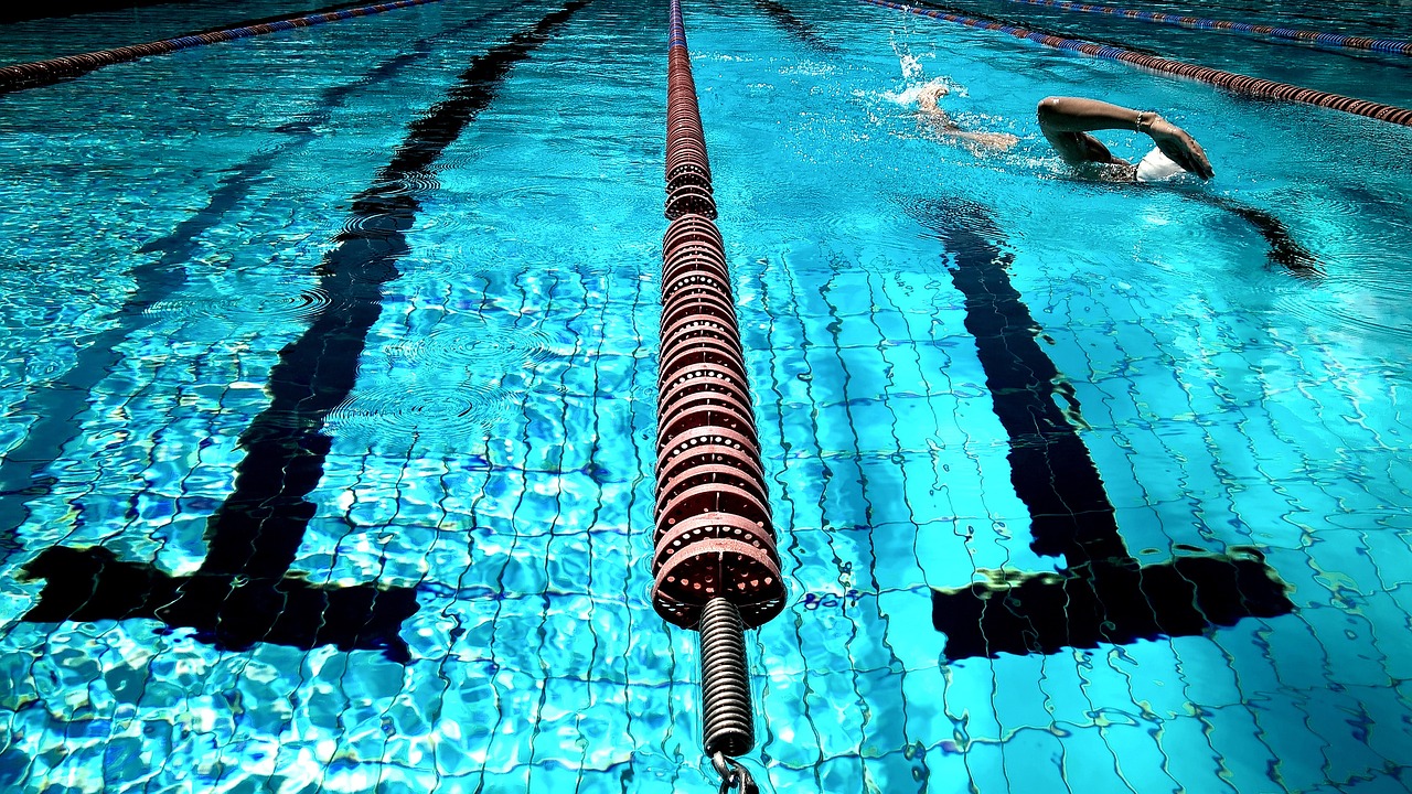 Ein Schwimmer in einem Schwimmbecken, umgeben von blauen Wasser und Schwimmbahnen.