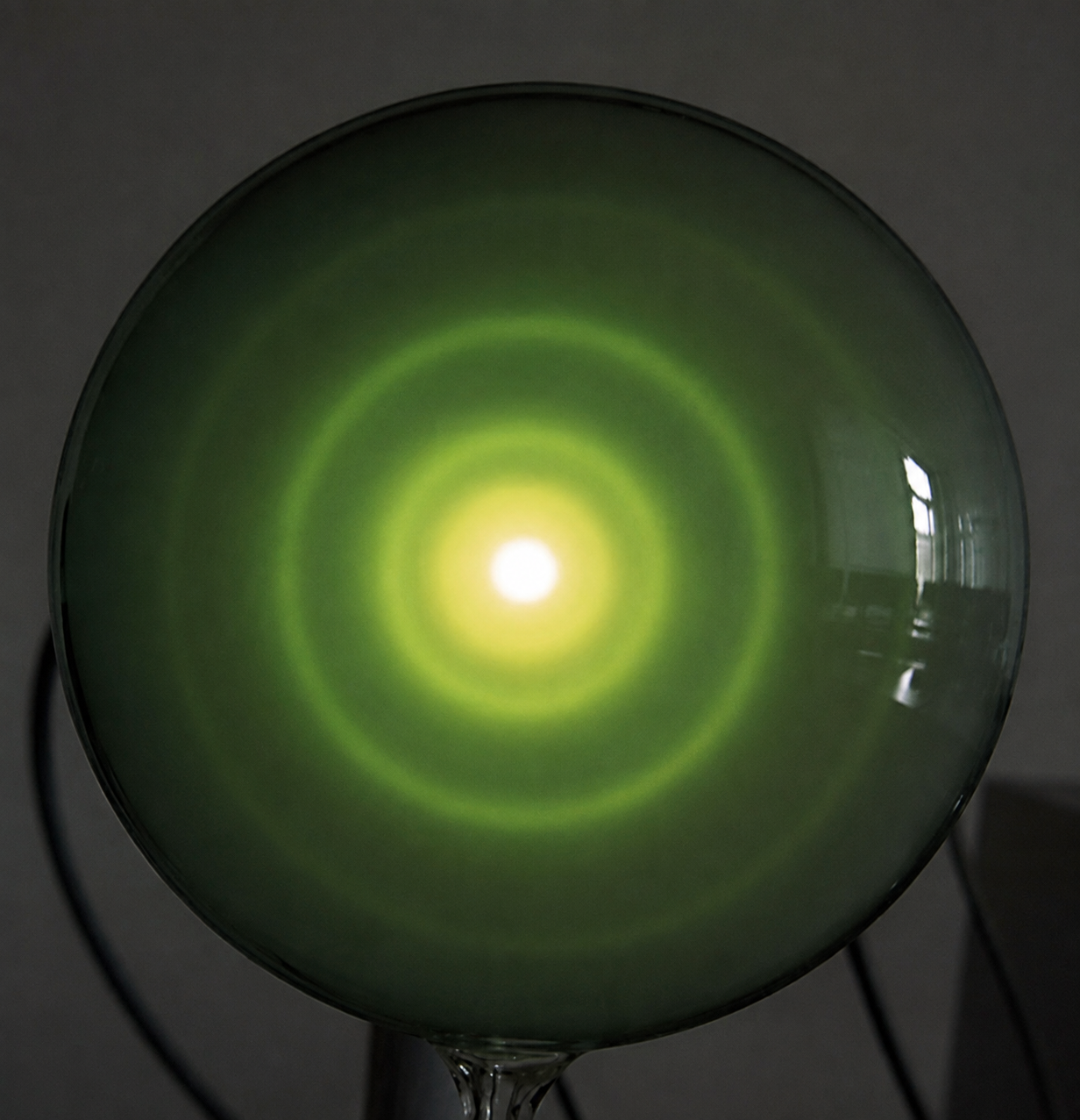 Grün leuchtende Kugel mit konzentrischen Lichtkreisen