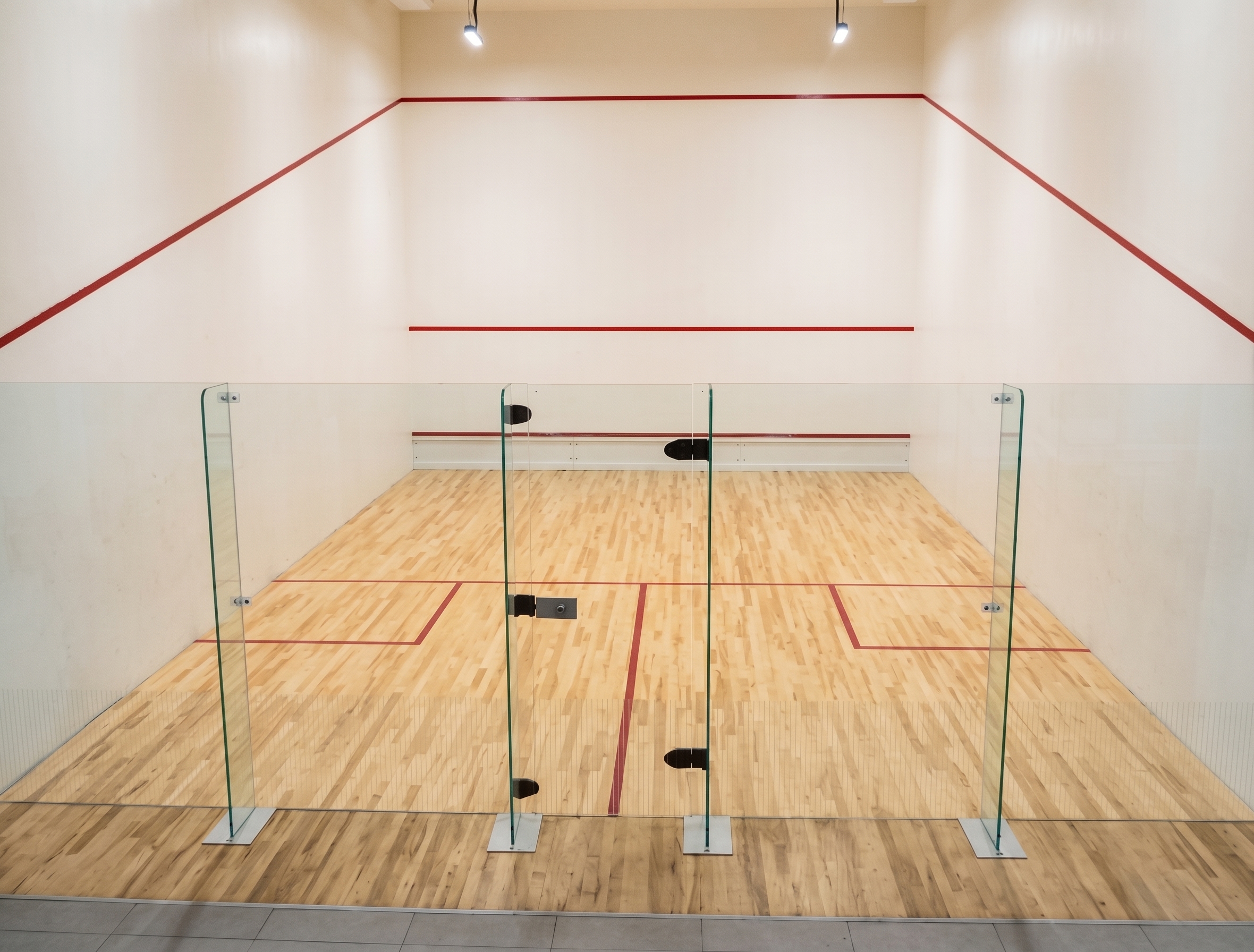Squashplatz mit Glaswänden und Holzfußboden