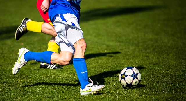 Zwei Fußballspieler auf dem Feld, einer dribbelt den Ball.