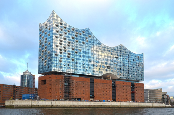 Moderne Architektur eines Gebäudes mit geschwungener Fassade und gemischten Materialien am Wasser.