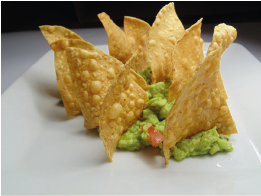 Tortilla-Chips serviert mit Guacamole und Tomatenstückchen auf einem weißen Teller.