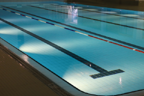 Ein leeres Schwimmbecken mit blauen Fliesen und beleuchteten Wasserbereichen.